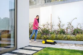 Person kehrt Terrasse mit Kehrmaschine